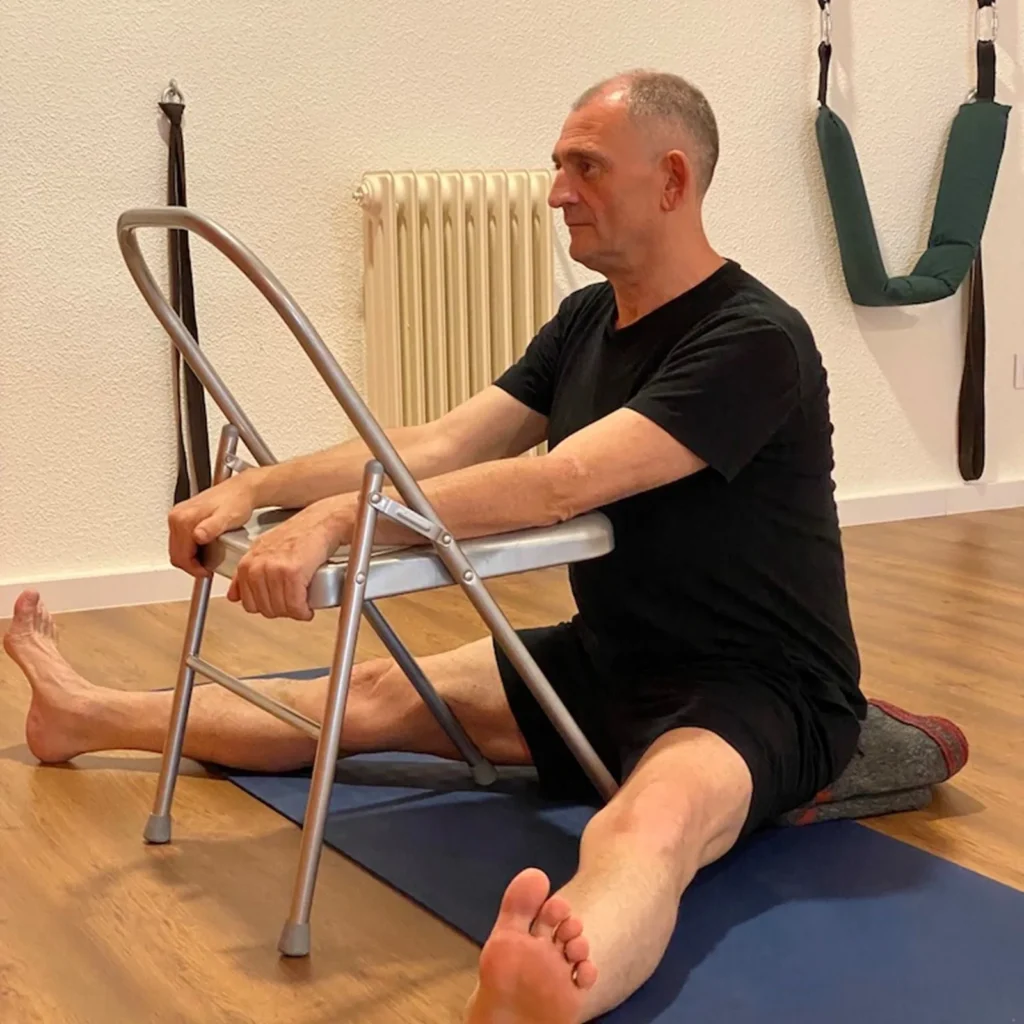Alumno sentado sujetando la silla en la clase de yoga para mayores